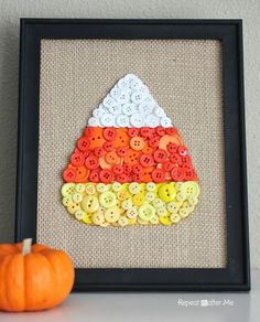 an image of a pumpkin made out of buttons in a frame with the caption saying,