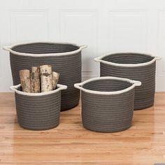 three woven baskets on the floor with wood logs in them