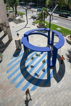 an aerial view of a blue sculpture in the middle of a plaza with people walking around it