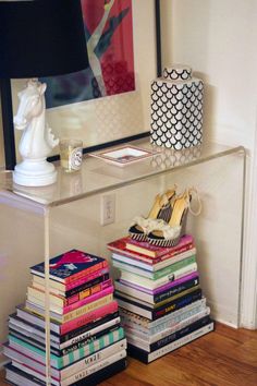 a stack of books sitting on top of a wooden floor next to a white vase