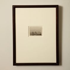 an old photo hanging on the wall with a wooden frame in front of it that is holding a small boat