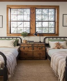 two twin beds in a small room with wooden windows and rugs on the floor