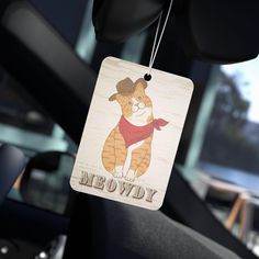 a cat hanging from the side of a car with a meowy tag attached to it