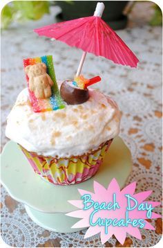 a cupcake with an umbrella and teddy bear on top that says beach day cupcakes