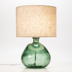 a green glass table lamp with a beige shade