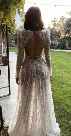 the back of a woman's dress with long sleeves and sequins on it