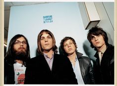 three men with long hair and beards standing next to each other in front of a white wall