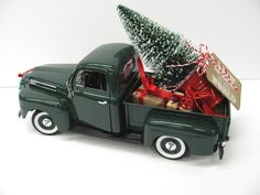 an old green truck with a christmas tree in the back and presents on the bed