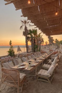 an outdoor dining area on the beach at sunset