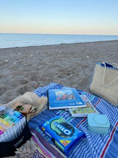 an open book and other items on a blanket at the beach