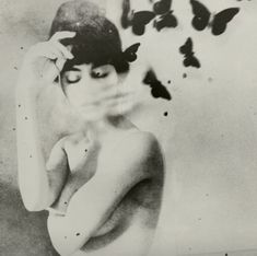 a black and white photo of a woman with butterflies flying over her head in the air