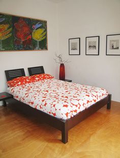 a bed sitting on top of a hard wood floor next to two pictures above it