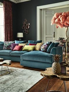 a living room filled with lots of furniture and pillows on top of a wooden floor