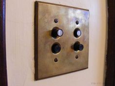 an old metal switch plate mounted to the side of a white wall with four black knobs