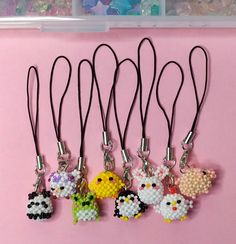 six keychains with different designs on them sitting next to each other in front of a pink background