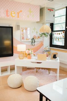 a living room with two white stools and a large flat screen tv on the wall