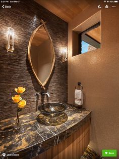 an image of a bathroom setting with marble counter tops and gold accents on the mirror