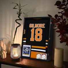 a hockey jersey is displayed on a mantle next to candles and a vase with flowers