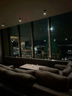 a living room filled with furniture next to large windows overlooking the city lights at night