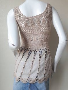 a white mannequin wearing a crocheted top and denim skirt with holes on the bottom