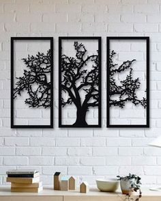 three black metal tree wall art pieces on a white brick wall in a living room