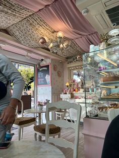 a woman standing in front of a counter filled with pastries