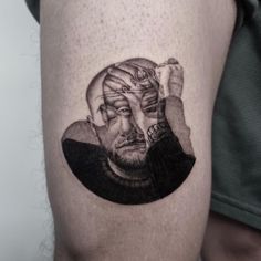 a black and white photo of a man's face in a circle tattoo on the leg