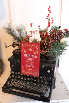 a christmas card sits on an old typewriter with pine cones, berries and holly