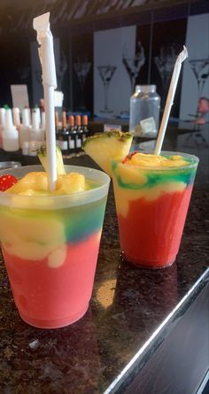 two cups filled with different colored drinks on top of a counter