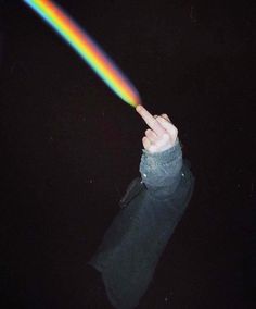 a person pointing at a rainbow light in the dark