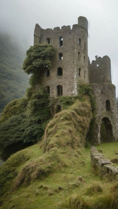 an old stone castle sitting on top of a lush green hillside