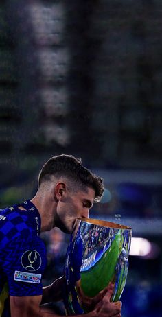 a male tennis player holding a trophy in his hand and looking down at the ground