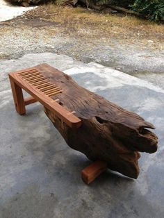 a bench made out of wood sitting on top of a cement ground next to trees