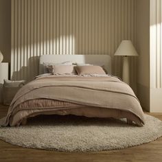 a large bed sitting on top of a wooden floor next to a wall with vertical blinds