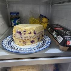 a cake sitting on top of a blue and white plate in a refrigerator next to an ice box