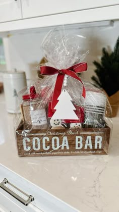 a wooden box filled with chocolates on top of a counter next to a christmas tree