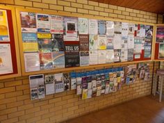 a wall covered in posters and papers next to a table