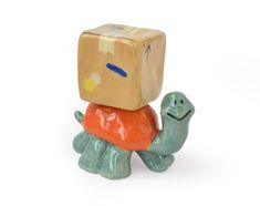 a small toy with a cube on top of it's head sitting on a turtle