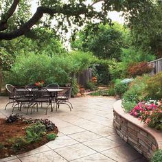 an outdoor patio with tables and chairs surrounded by flowers, trees, and plants in the background