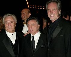 three men in tuxedos are posing for a photo at an event with other people