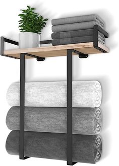 a shelf with towels and a potted plant on it next to a wall mounted towel rack