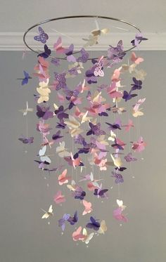 a mobile made out of paper butterflies hanging from the ceiling in a room with gray walls