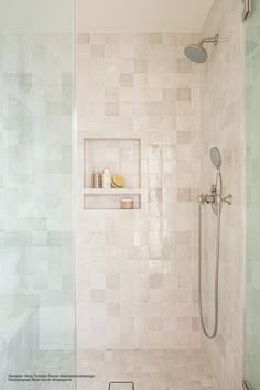 a walk in shower sitting next to a tiled wall