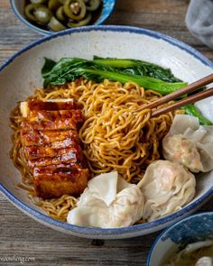 a bowl filled with noodles, meat and veggies next to chopsticks