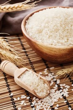 white rice in a wooden bowl next to some ears of wheat