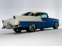 an old blue and white car is parked on the floor in front of a wall