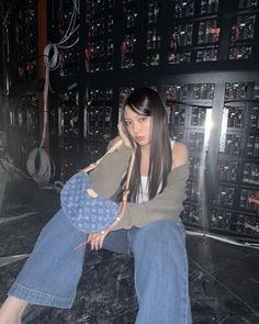 a woman sitting on top of a table next to a wall covered in lots of wires