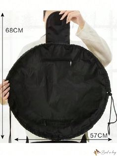 a person holding up a black round object in front of their face with measurements on it