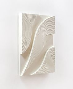 a white sculpture on the wall with wavy lines painted on it's sides and bottom