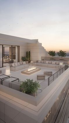 an outdoor fire pit on the roof of a modern home at sunset or dawn with patio furniture and potted plants